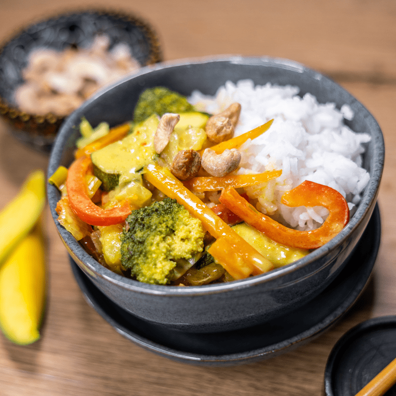 Ein Teller mit Mango Curry, garniert mit frischen Kräutern und serviert mit Reis